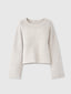 A cropped, long-sleeve knit sweater in a warm off-white or cream color with subtle speckled flecks throughout, featuring ribbed trim at the crew neck, cuffs, and hem, shown against a light gray background.