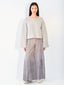 A model stands against a plain white studio background wearing a light beige knit long-sleeve cropped sweater and wide-leg gray pants.