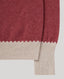 Close-up of a knit sweater showing a heathered dusty rose red body with a contrasting ribbed cream cuff and hem.