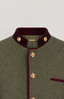 Close-up of a textured olive green herringbone jacket with a deep burgundy velvet collar, matching trim, and gold-tone decorative buttons.