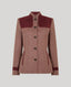 A women's tailored jacket in a heathered dusty rose-brown fabric with contrasting dark burgundy suede-like shoulder yokes, matching trim at the cuffs, and a stand collar, shown on a light gray background.