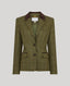 An olive green tweed blazer with a subtle windowpane check pattern, featuring a contrasting dark brown inner collar and dark buttons, displayed on a neutral gray background.