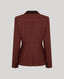 A structured blazer shown from the back, featuring a reddish-brown windowpane check pattern and a contrasting dark brown collar, set against a solid light gray background.