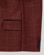 Close-up of a tailored jacket sleeve in a deep burgundy red fabric with a subtle tan windowpane check pattern, featuring a flap pocket and three dark buttons.