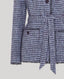 Close-up of a lavender blue boucle jacket with covered buttons on a light gray background