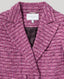 Close-up of a pink boucle blazer with a brand label on a gray background