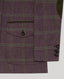 Close-up of a purple herringbone tweed jacket with a green windowpane plaid pattern, featuring a flap pocket with a dark button and three dark buttons on the sleeve cuff.