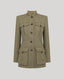 A structured tweed jacket in a muted olive-beige color, featuring a mandarin collar, dark buttons, and four front flap pockets, shown on a neutral light gray background.