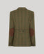 The back view of a green plaid blazer with brown suede elbow patches and a matching green plaid pattern, shown on a solid gray background.