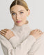 Close-up on Model wearing Lambswool High-Neck Sweater in Swansdown Ivory showing rib detail on neck and cuffs 