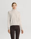 Model wearing Lambswool High-Neck Sweater in Swansdown Ivory with brown trousers 
