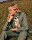 Woman in a green outfit sitting in a grassy field