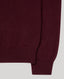 Close-up of a ribbed knit sweater in a deep burgundy or maroon color, showing the texture and cuff detail against a light gray background.