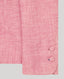 Close-up of a pink herringbone fabric with covered buttons at the cuff on a grey background