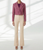 Person wearing a pink boucle jacket and beige pants on a white background