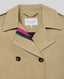 Close-up on the Trench coat in classic beige colour with tortoiseshell buttons, showing the pink and green lining 