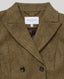 Close-up of a brown and beige herringbone tweed double-breasted blazer by Really Wild London, showing the collar, white brand label, and dark buttons.