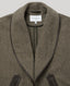 Close-up of a herringbone patterned jacket in olive brown with dark brown trim and a white neck label reading 'REALY MILD LONDON'.