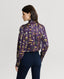 Back of Model wearing Plumage Feather Print Silk Fixed Tie Neck Blouse in Aubergine with jeans 