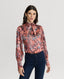 Model wearing Plumage Feather Print Silk Fixed Tie Neck Blouse in Coral Red with jeans