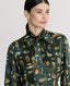 Close-up on Model wearing Plumage Feather Print Silk Fixed Tie Neck Blouse in green 