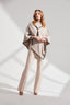 Woman wearing a beige cape and pants on a white background