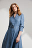 Model wearing a blue dress with a belt against a plain background