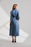 Back of model wearing a blue dress standing against a white background