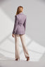 Back of model wearing purple belted jacket with beige trousers and heels 