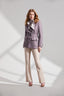 Model wearing a light purple jacket and beige pants on a white background