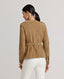 Back of Model wearing a brown suede jacket with a belt with white trousers 