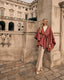 Woman in a pink cape standing in front of a classical building