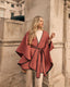 Woman wearing a pink cape in front of a stone building