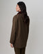 A woman shown from the back wearing a brown tweed blazer with a dark burgundy collar, paired with brown trousers, against a plain light gray studio background.