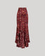 A high-waisted, floor-length ruffled skirt in a deep burgundy red, featuring an all-over abstract print of small colorful shapes and lines. The skirt has a structured waistband and cascading ruffle layers.