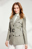 Model wearing Sage Green Safari Jacket with tortoiseshell buttons and belt buckle with white trousers and silk blouse 
