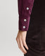 Close-up on cuff of Spencer-Stretch Corduroy Shirt in Oxblood Burgundy featuring mother of pearl buttons with brown trousers