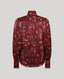 A long-sleeve button-up shirt in a deep burgundy red, featuring an all-over feather print in brown, beige, and muted orange tones. The shirt is displayed flat against a solid light gray background.