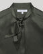 Close-up of a dark olive green satin blouse with a tie-neck detail, featuring a white neck label that reads 'REALLY WILD PARIS'.