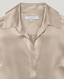 Close-up of a satin button-up shirt collar in a warm champagne beige color, with a visible neck label reading REALLY WILD.