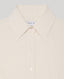 Close-up of a cream-colored collared button-down shirt with white buttons, showing the inner neck label with partial text 'REALLY WILD'.