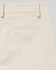 Close-up of beige pants with a pocket detail on a light gray background