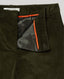 Close-up of olive green corduroy trousers showing the interior waistband, black satin lining, and bright orange contrast piping. A white brand label reading REALLY WILD is visible at the back waistband.