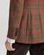 Model wearing the Wellington Tweed Longline Jacket in Burnt Orange and Oxblood Red check showing the leather buttons on the cuff 