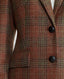 Close-up of The Wellington Tweed Longline Jacket in Burnt Orange and Oxblood Red check showing the leather buttons and pocket flaps 