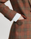 Model wearing the Wellington Tweed Longline Jacket in Burnt Orange and Oxblood Red check showing the Branded burnt brick jacquard lining in the pocket 