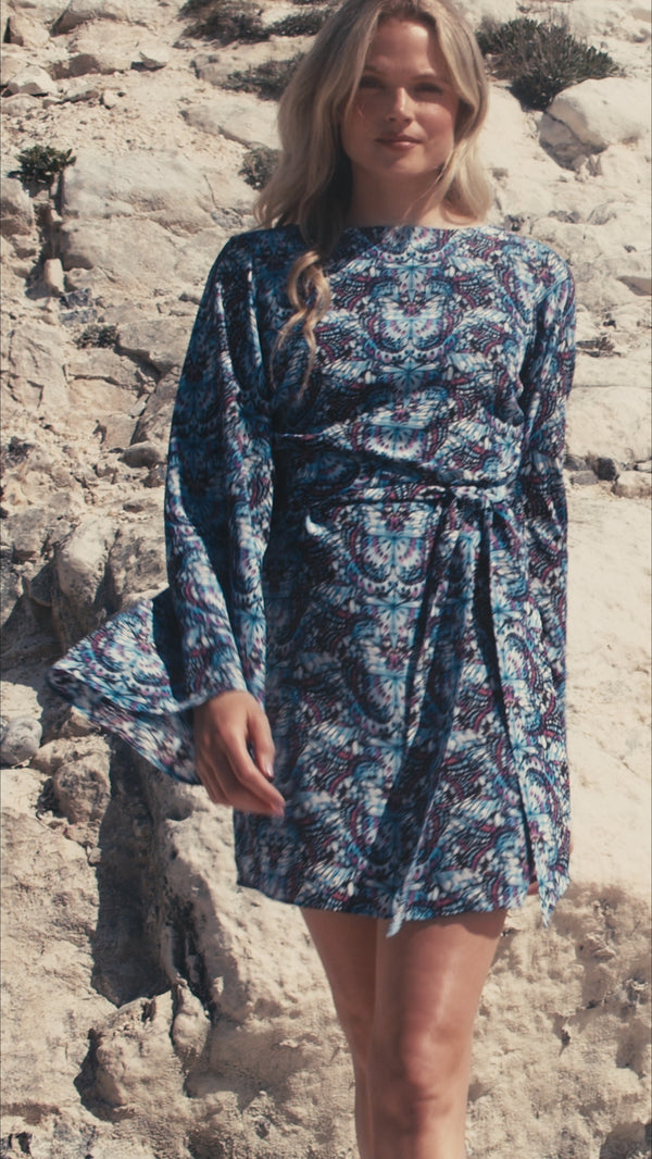 Model wearing butterfly print blue cocktail dress on the beach